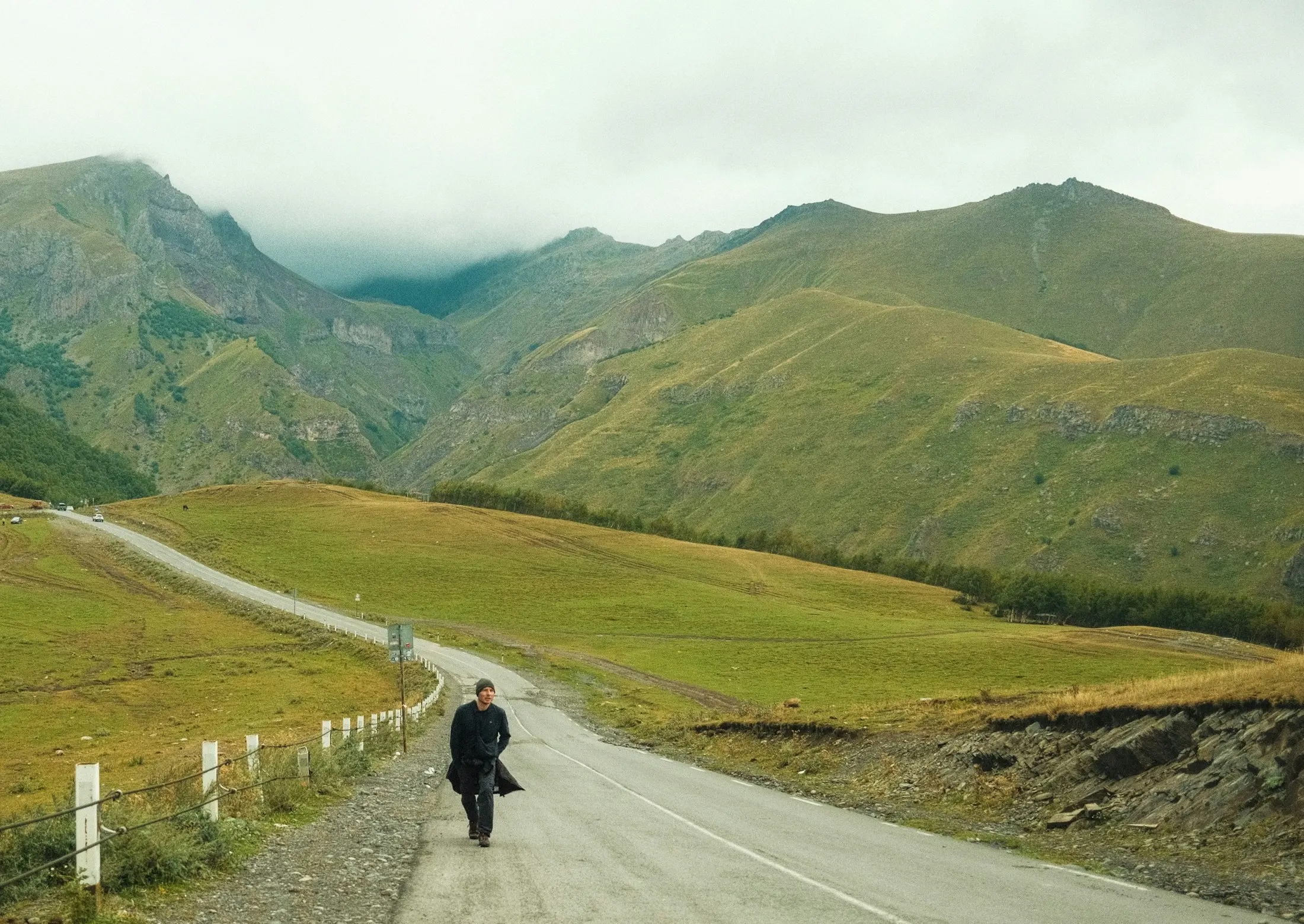 A lone figure walking along a winding mountain road