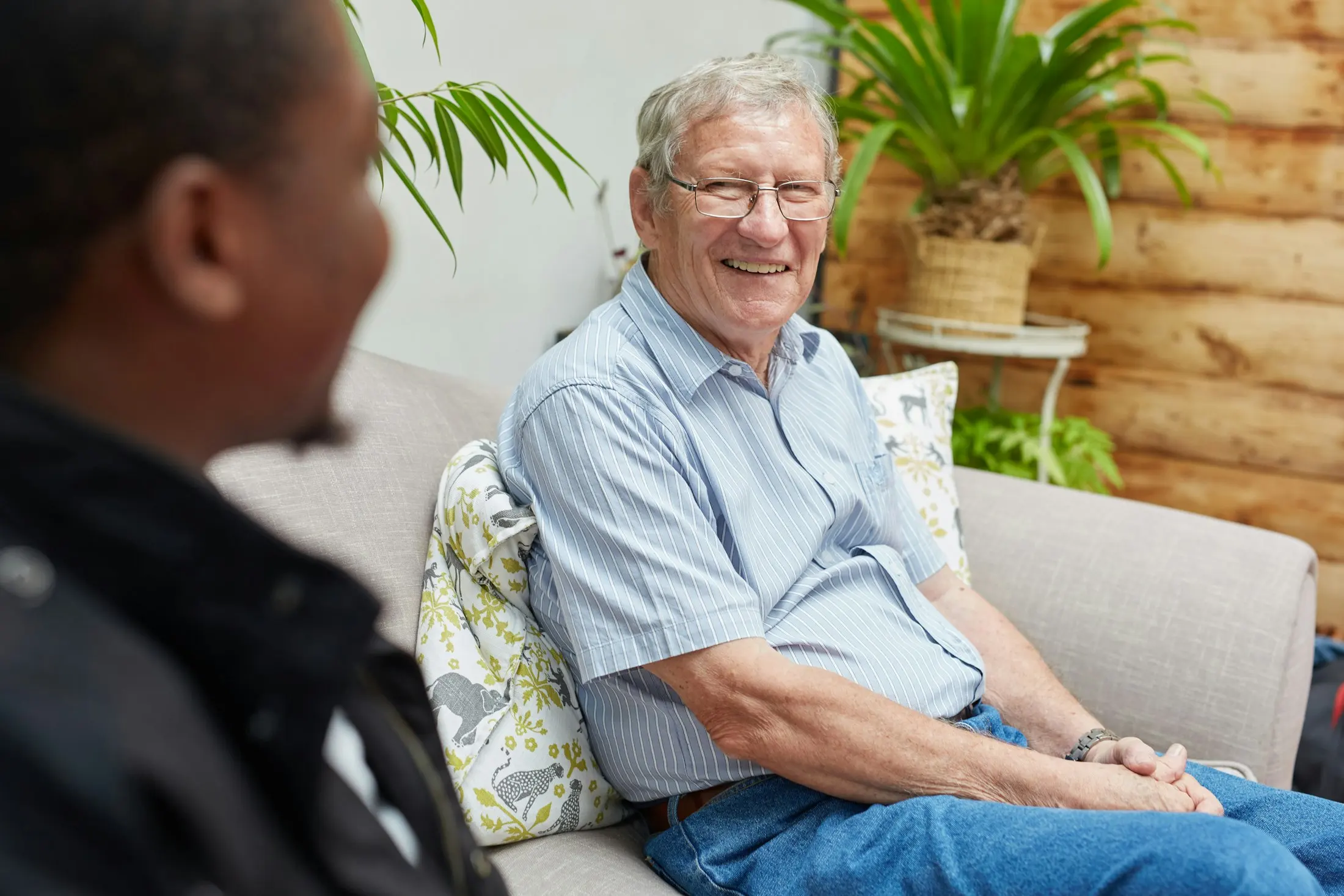 An older man smiling as he listens to a younger man during a conversation