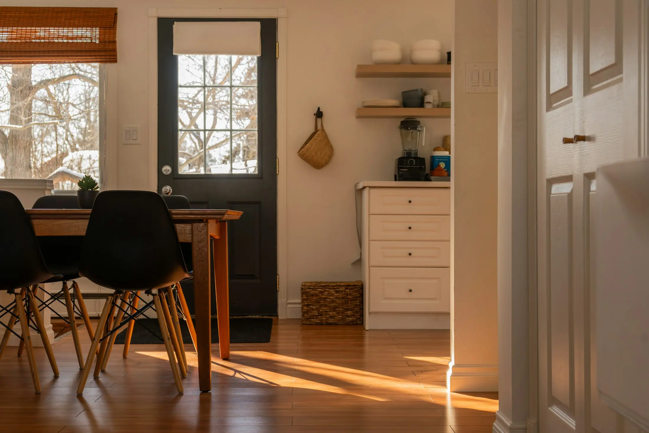 Low morning sunlight streaming across a wooden floor into a quiet kitchen